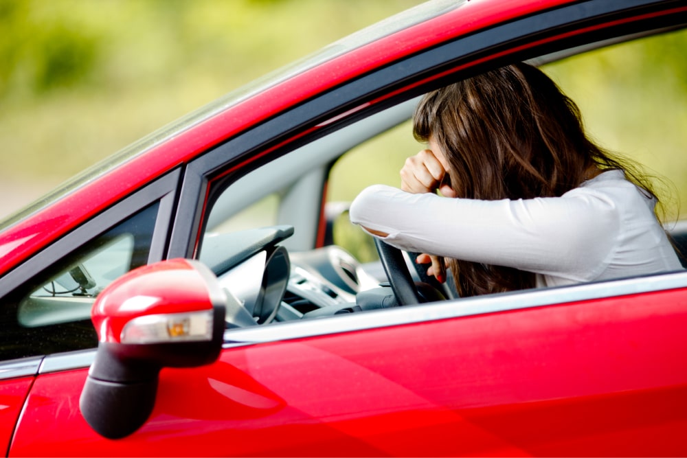 kara za brak OC załamana kobieta w czerwonym samochodzie