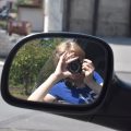 młoda dziewczyna siedzi w samochodzie, Robi zdjęcie, widać ją w bocznym lusterku